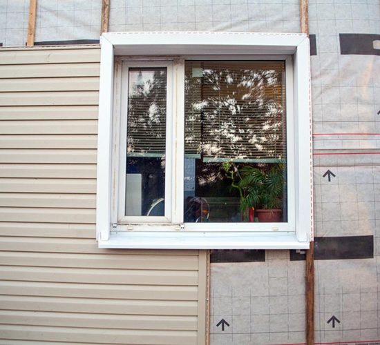 Wall covering of the frame house with panels of vinyl siding of gray color. Decorating the house with siding. The master updates the look of the old house with siding.